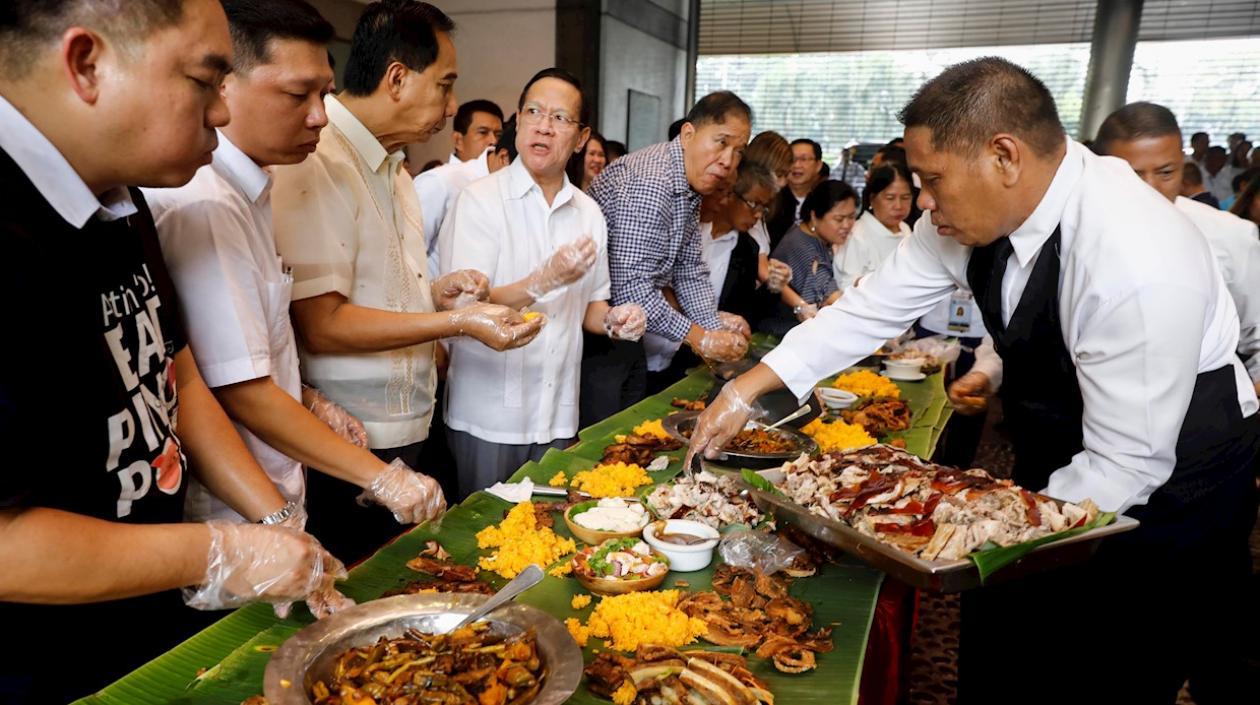 Funcionarios y comerciantes comieron platos de carne de cerdo para demostrar que la carne que se vende localmente es segura.
