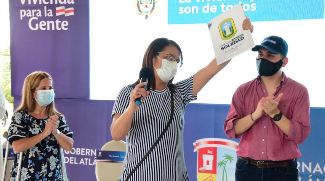 Una beneficiaria exhibiendo el título de vivienda,