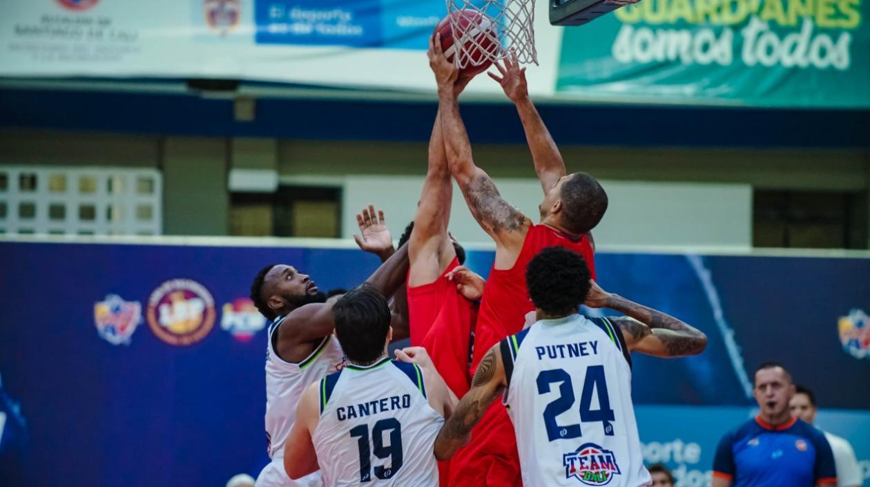 Gianluca Bacci y Jonathan Rodríguez luchan bajo el aro, ante la marca de tres jugadores del Team Cali.