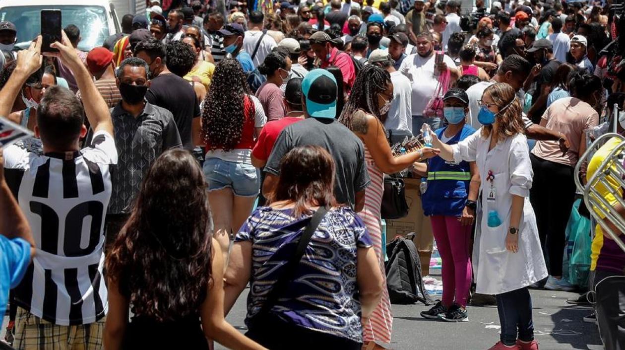 Una enfermera desinfecta las manos de las personas que caminan en una concurrida vía comercial hoy, en el centro de Sao Paulo (Brasil).