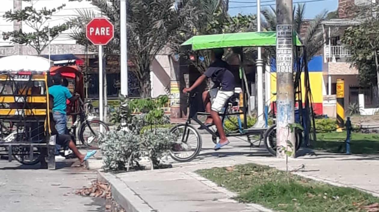 Una persona movilizándose en bicitaxi por el sendero de un parque.