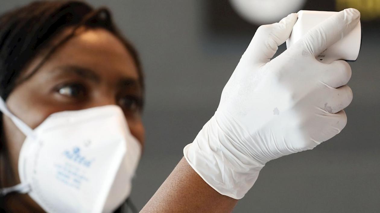 Funcionarios toman la temperatura de los ciudadanos que llegan este jueves al aeropuerto internacional El Dorado