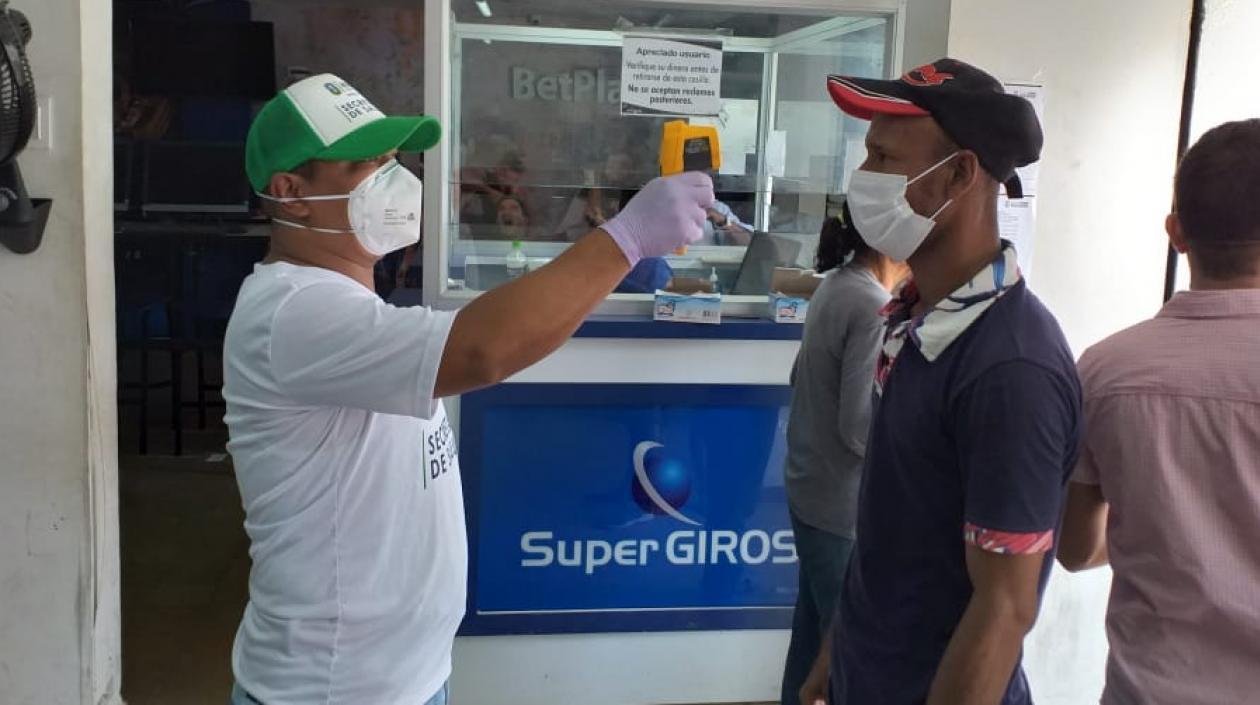 Un funcionario toma la temperatura a personas que se acercan a reclamar subsidios del adulto mayor en Soledad.