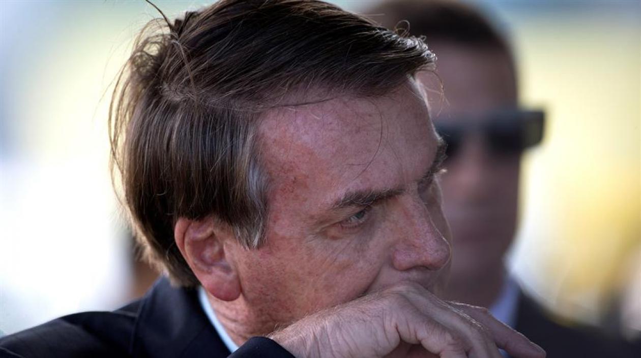 Jair Bolsanoro, presidente de Brasil, tocándose la cara con las manos en tiempos de coronavirus.