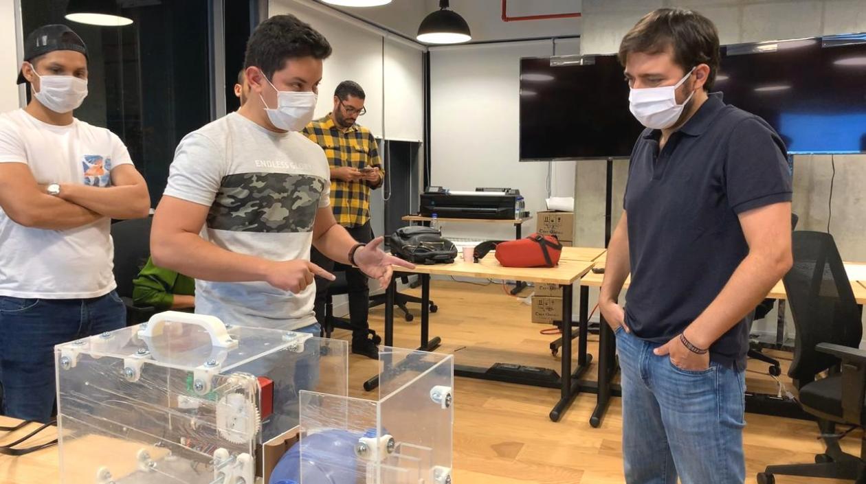 Jóvenes innovadores y alcalde muestran un equipo de ventilación mecánica.