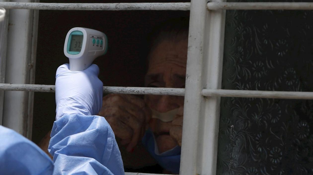 Una enfermera toma la temperatura de un adulto mayor.