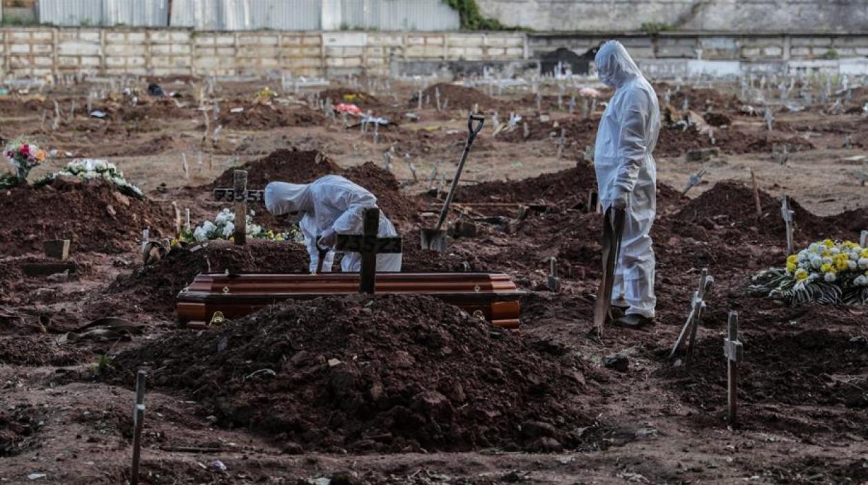 Empleados de una funeraria realizan el entierro de una persona que falleció a causa del Covid-19 en el cementerio de Caju, en la zona norte de Río de Janeiro.