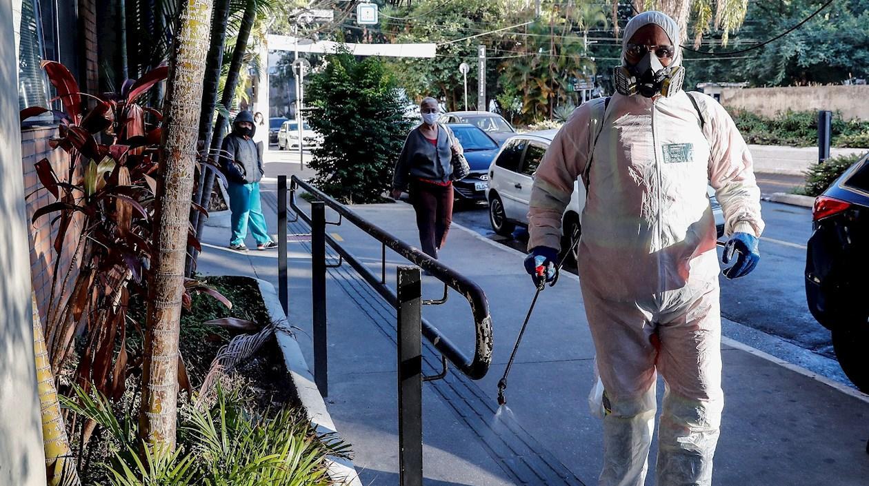 Un agente municipal desinfecta este jueves, la fachada de una unidad de salud en Sao Paulo. 
