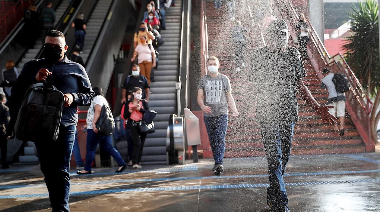 Usuarios pasan por una cabina de desinfección mientras salen de una estación del metro, en el centro de la ciudad de Osasco, en Sao Paulo (Brasil). 