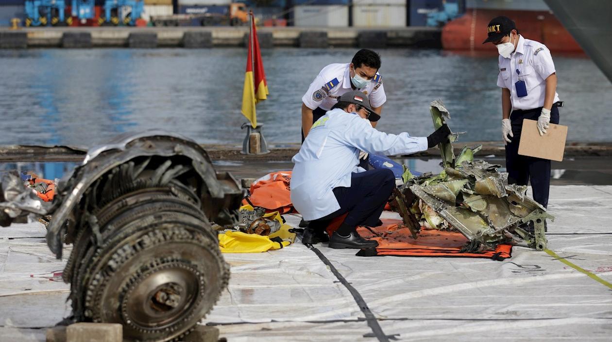 Investigadores con algunas partes del avión accidentado en Indonesia.