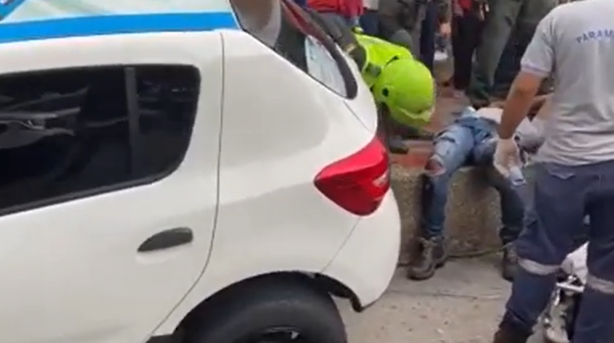 Lugar de los hechos en los que se observa a uno de los presuntos delincuentes tendido en la acera.