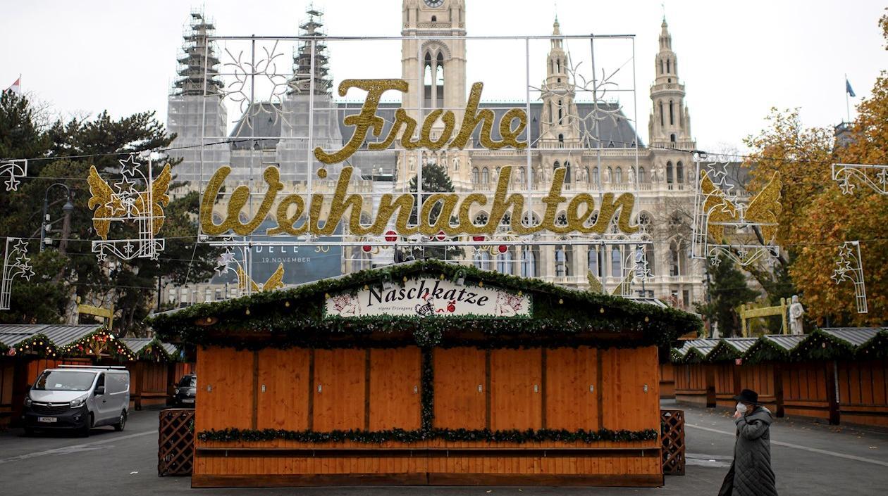 Una mujer camina por un mercado navideño cerrado frente al ayuntamiento de Viena. 