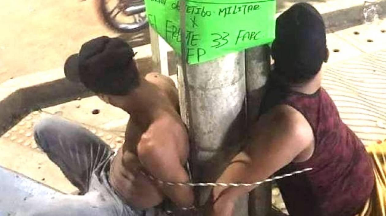 Los dos hombres atados en el poste.