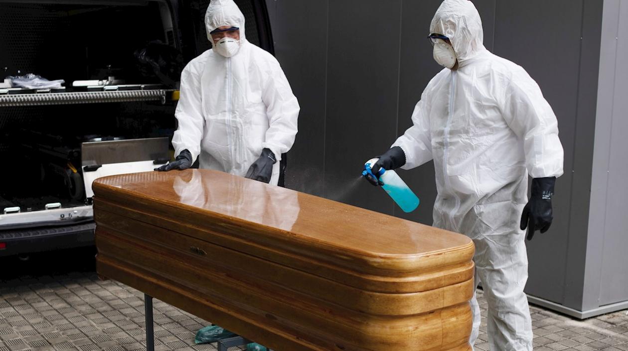Trabajadores de un tanatorio sacan del hospital un ataúd para proceder a su desinfección antes de trasladarlo al cementerio. 
