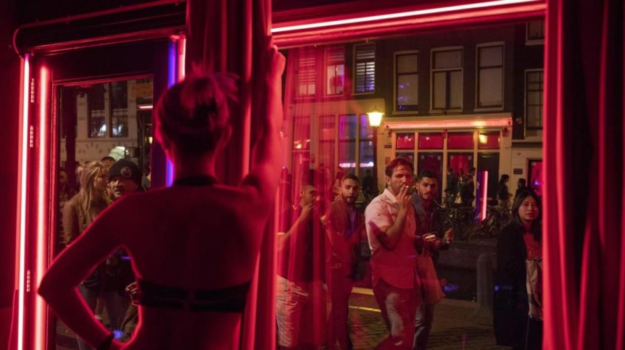 Jóvenes frente a uno de los escaparates del barrio Rojo de Amsterdam.