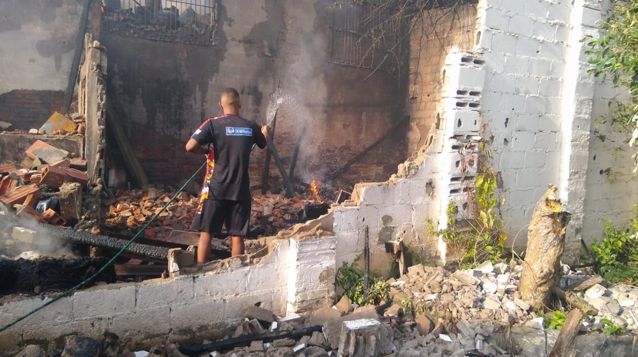 Una persona riega agua en el lugar para evitar que el fuego vuelva a a surgir. 