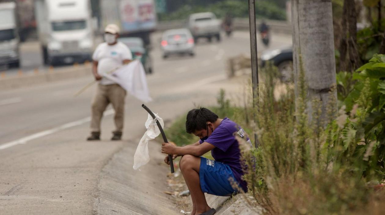 Un adolescente ondea una bandera blanca en una carretera pidiendo ayuda. 