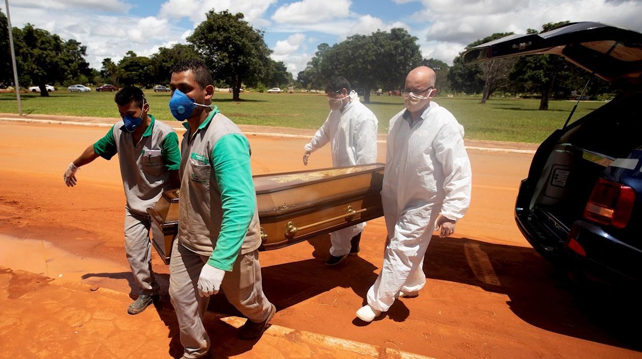 Trabajadores cargan un féretro con una víctima mortal de Covid-19 rumbo a su entierro en el cementerio Campo da Esperança, en Brasilia (Brasil). 