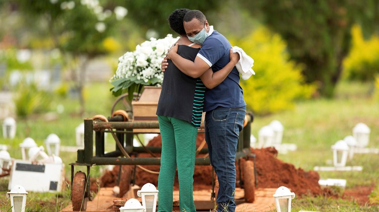 Un grupo de personas asiste al entierro de un ser querido víctima de covid-19 hoy, en el cementerio Campo da Esperança, en la ciudad de Brasilia (Brasil).