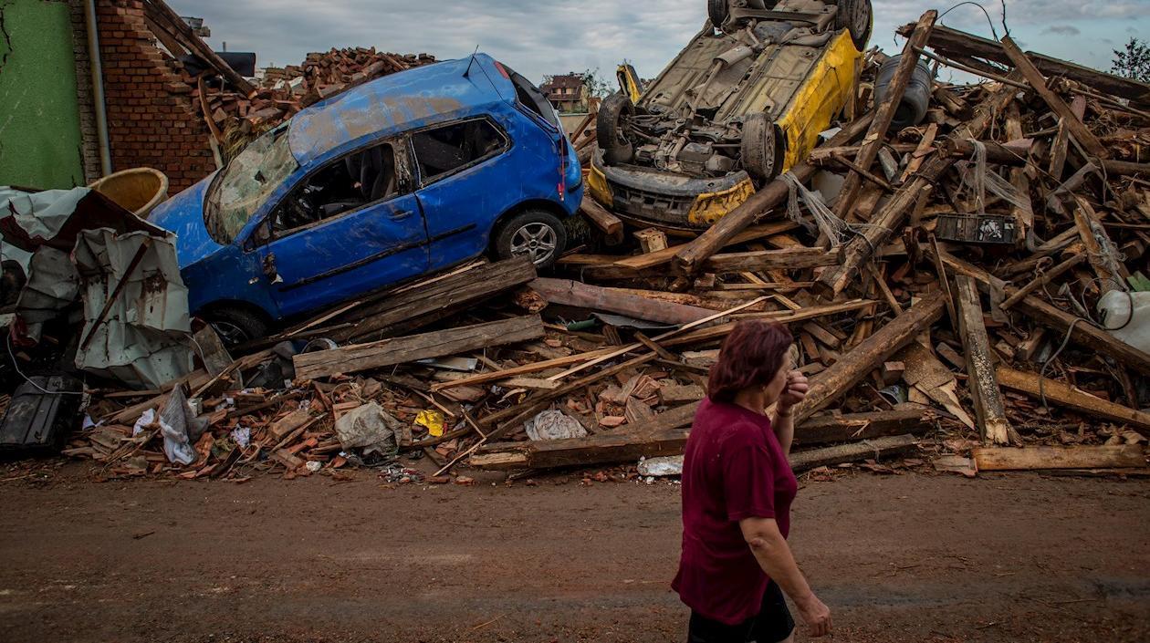 Una mujer pasa junto a automóviles dañados por el tornado Mikulcice, República Checa.