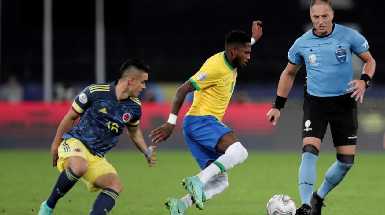 Rafael Santos Borré, delantero colombiano, marca a Fred ante la mirada de Néstor Pitana. 
