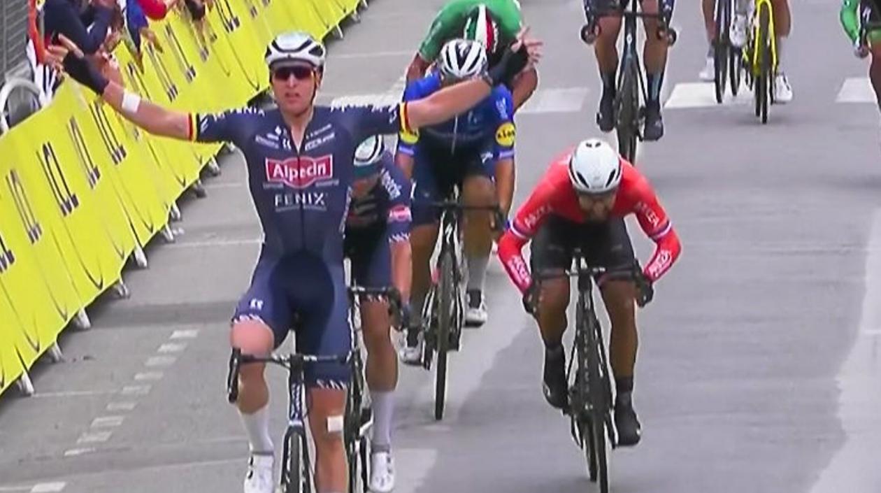 El belga Tim Merlier levanta los brazos en la meta.