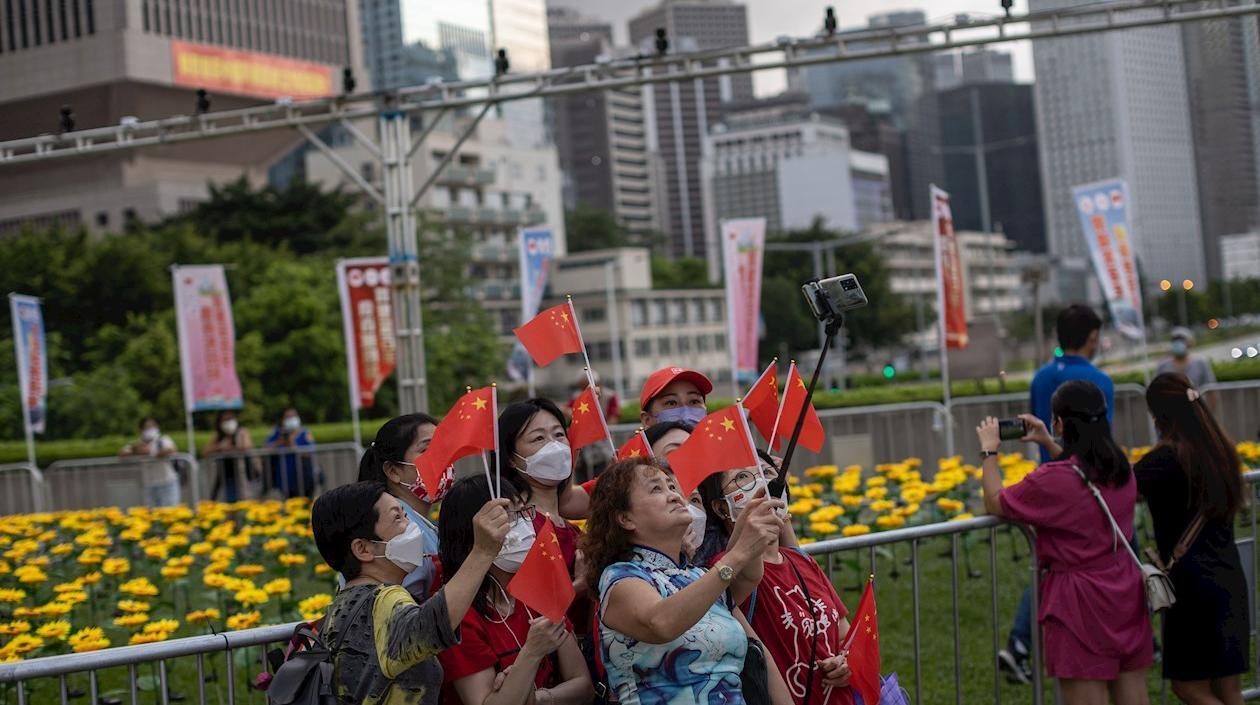 Un grupo de mujeres se toma fotografías mientras sujetan banderas chinas en Hong Kong, China. 