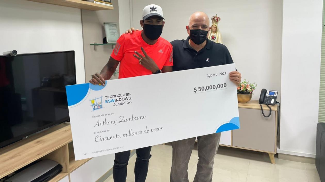 Anthony Zambrano recibe el cheque de manos de Christian Daes. 