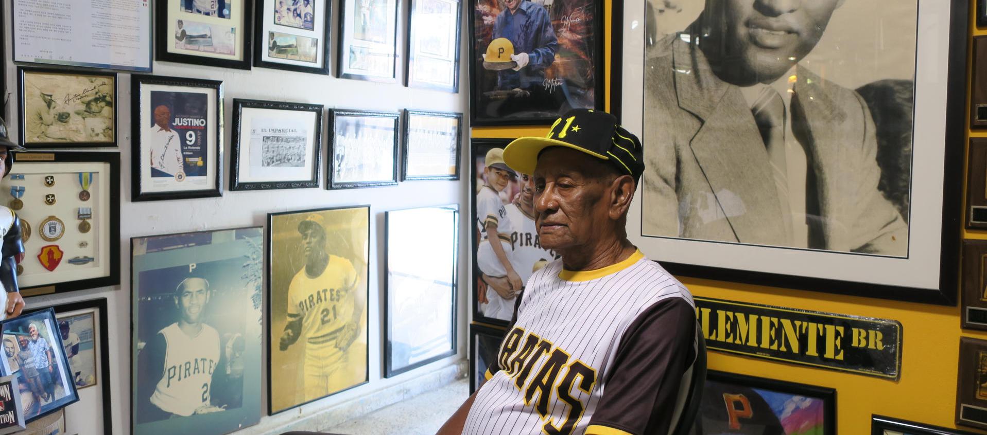 Justino, hermano de Roberto Clemente, rodeado de fotos del legendario beisbolista.