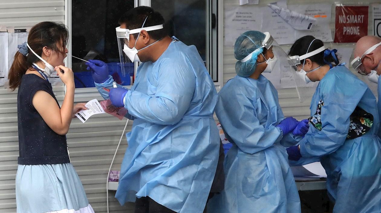 Un funcionario de la salud toma una muestra a una mujer en Australia, para detectar el Covid-19.