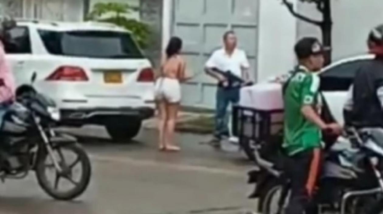 Julio César Yamin Berardinelli, con fusil en mano, discute con los ocupantes de un automóvil blanco.