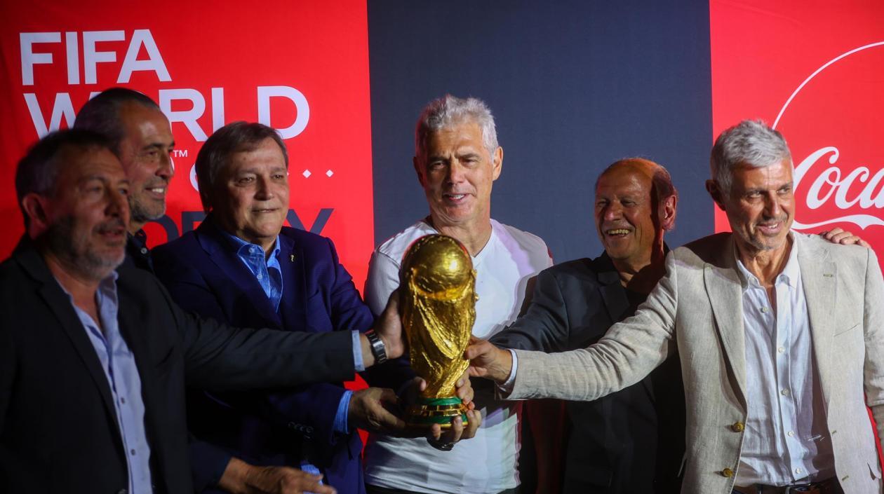 Los exfutbolistas argentinos Carlos Tapia, Sergio Batista, Daniel Bertoni, Alberto Tarantini, Omar Larrosa y Sergio Giusti posan junto al trofeo de la Copa Mundial.