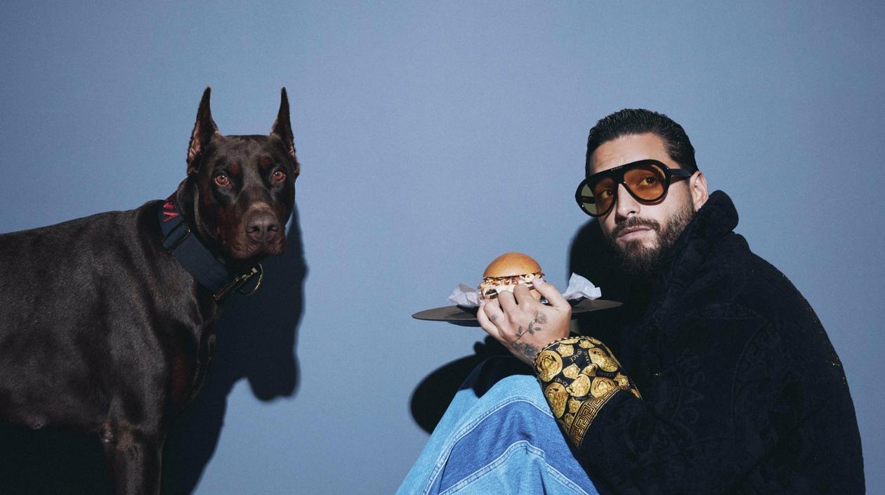 Maluma rodeado de hamburguesas y hot dogs (perros calientes).