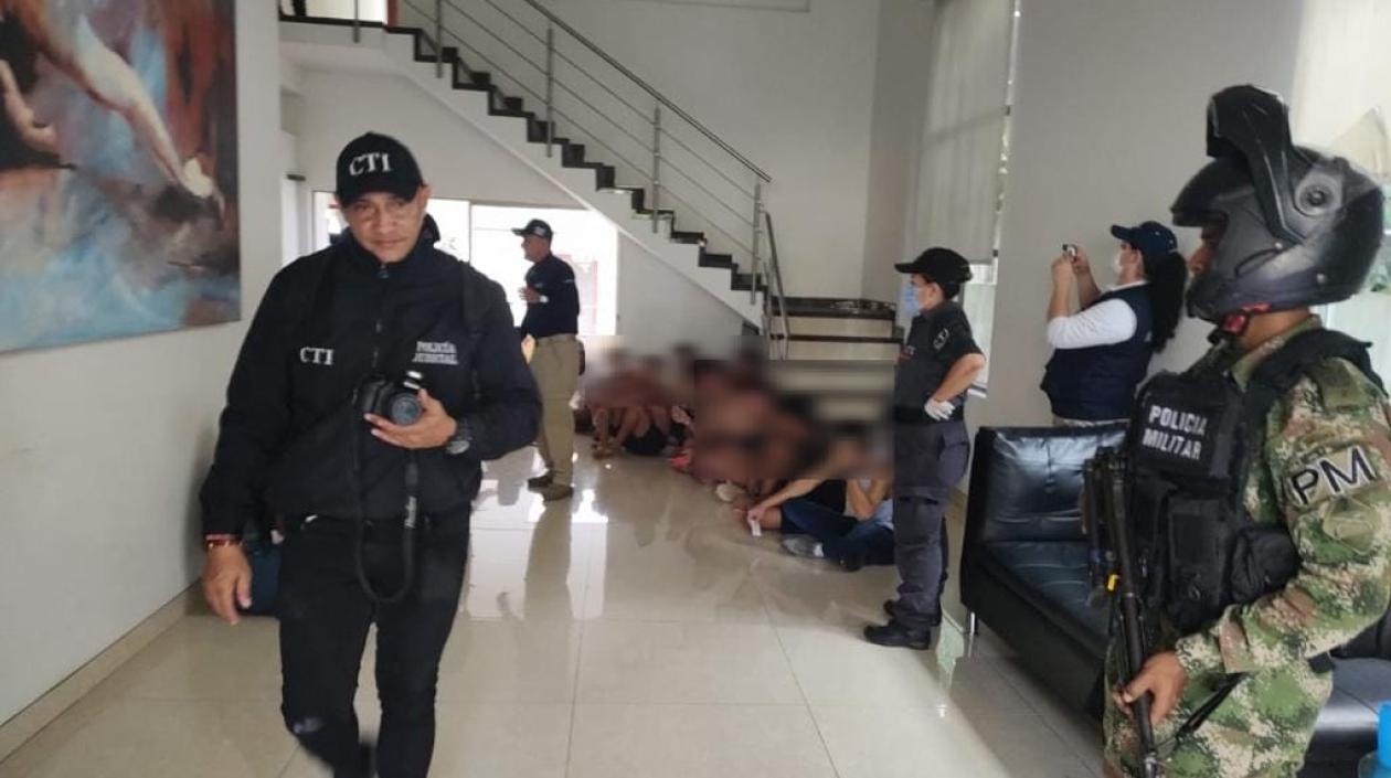 Las autoridades en la vivienda donde hallaron a 17 hombres víctimas de explotación laboral y sexual. 