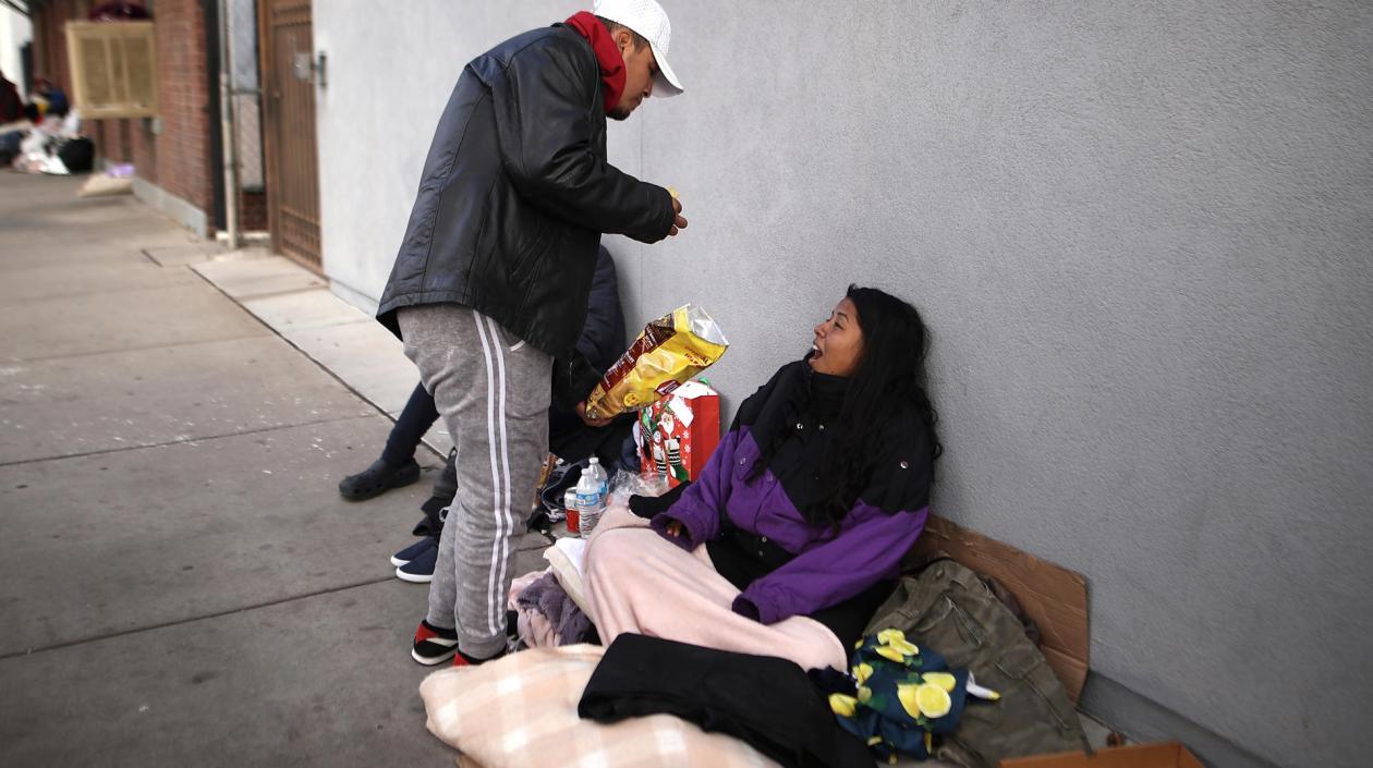 Inmigrantes indocumentados mexicanos comen en el suelo en una calle de la ciudad fronteriza de El Paso, Texas.