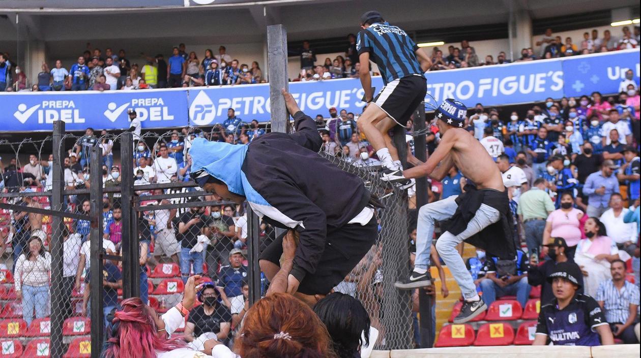 Hinchas del Querétaro se vuelan la cerca que separa la tribuna de la cancha.