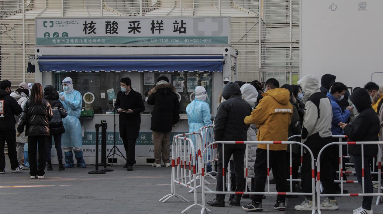 Numerosas personas, protegidas con mascarillas, hacen cola para que les realicen test de antígenos y descartar que sufran de COVID-19 en Pekín, China, en una foto de archivo. 
