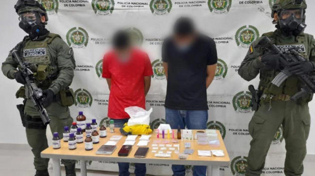 Los dos capturados y parte de las drogas incautadas.