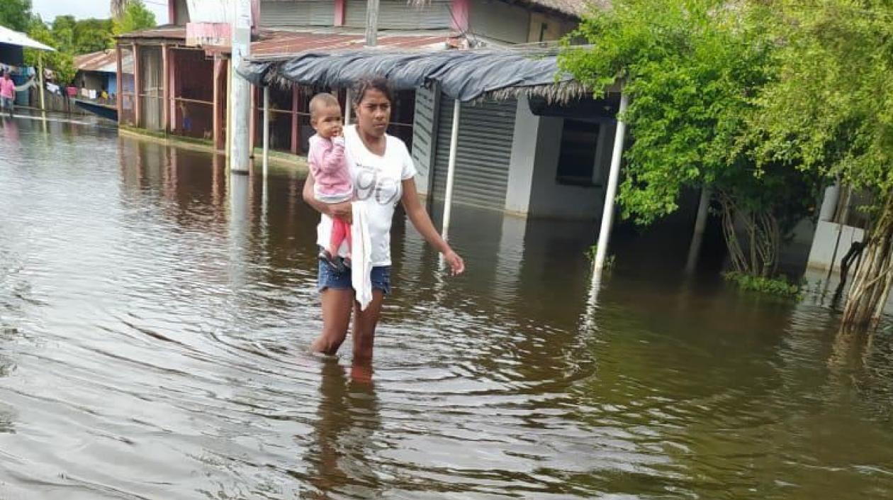 Una mujer y su hijo caminan entre las aguas desbordadas en Sucre.