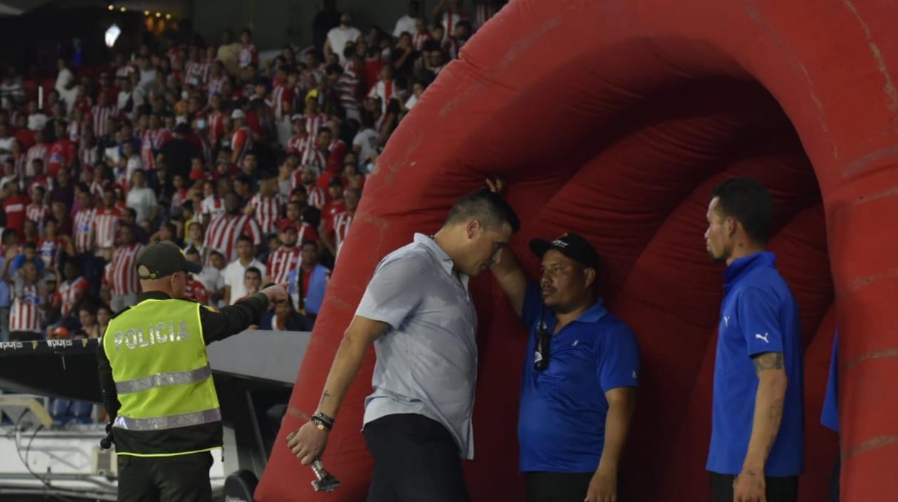 Juan Cruz Real, entrenador de Junior, se marcha al camerino con la escultura del Cristo Negro, bajo los insultos de los hinchas. 