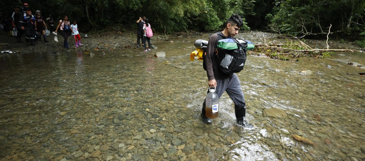 Migrantes cruzan un río en el Tapón del Daríen.