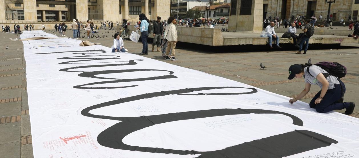 Imagen de referencia de personas que escribieron mensajes sobre una tela durante la conmemoración de los seis años de la firma del Acuerdo de Paz.