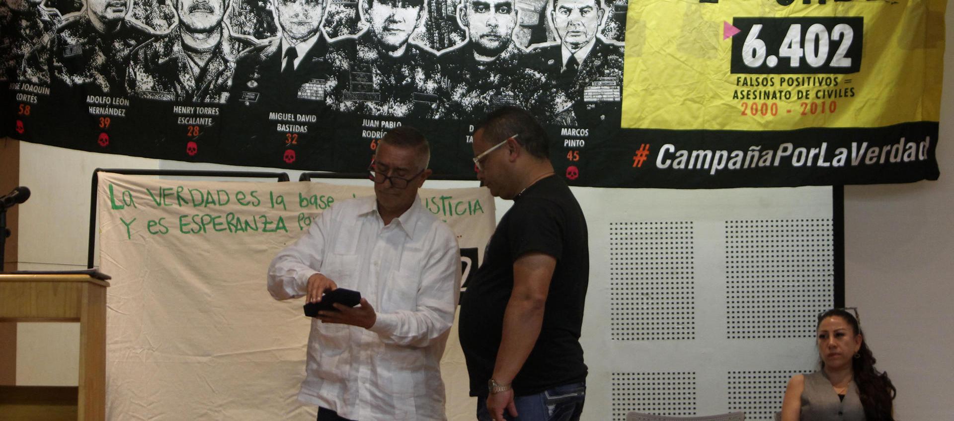  El coronel (r) Jaime Humberto Pinzón entrega una medalla otorgada por sus actuaciones militares hace 18 años a José Alexander Castro, del colectivo Tejiendo Memorias.