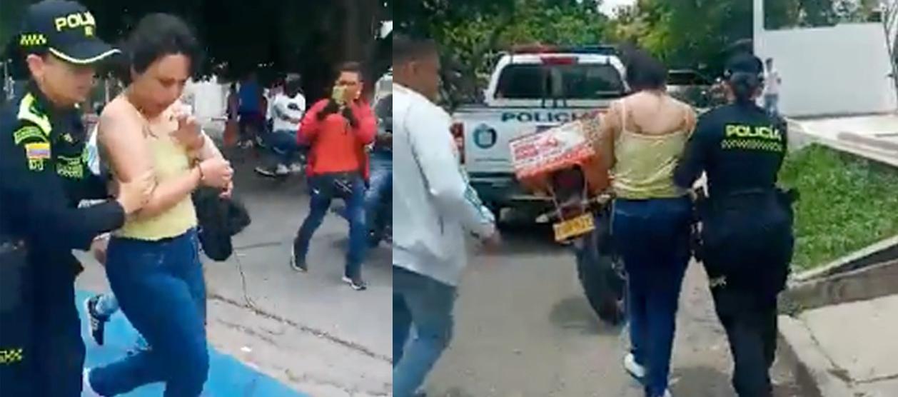 Policías conducen a una mujer luego de robo de un camión de valores cargado de dinero.