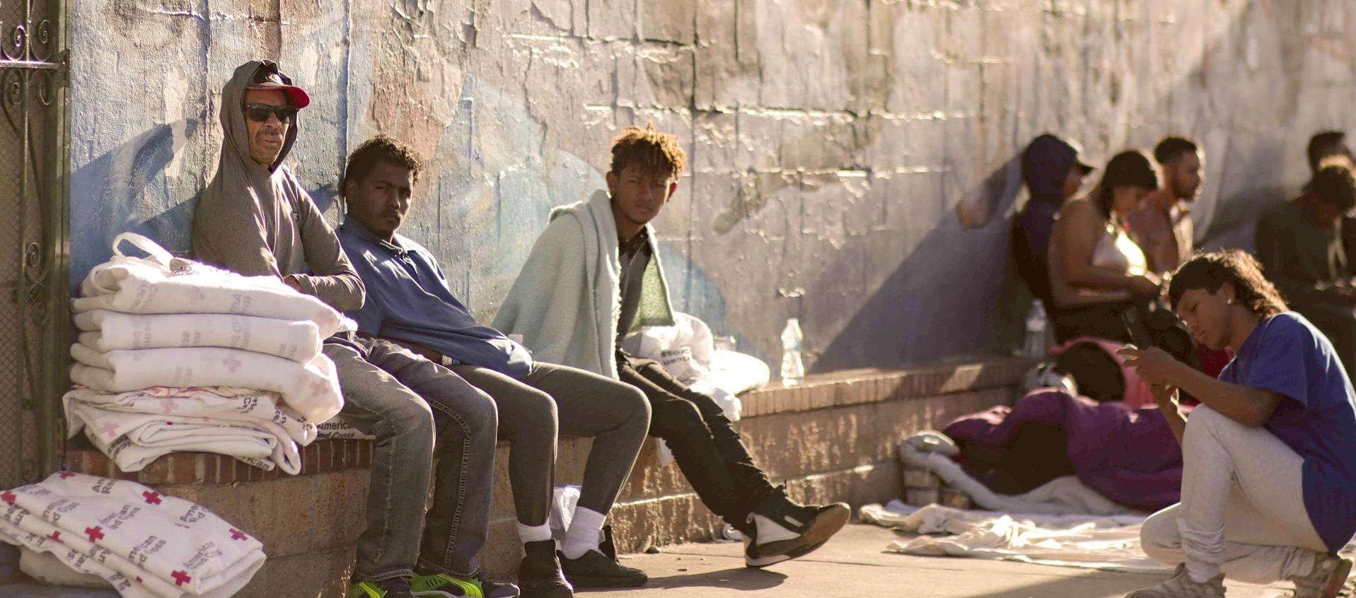 Varios migrantes esperan el sábado en una calle en El Paso, Texas 