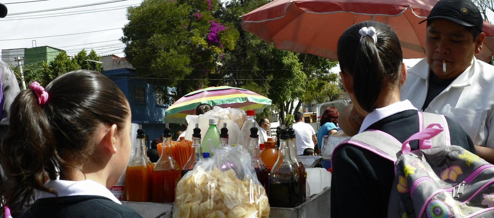 Unas niñas estudiantes compran frituras afuera de un colegio en Ciudad de México