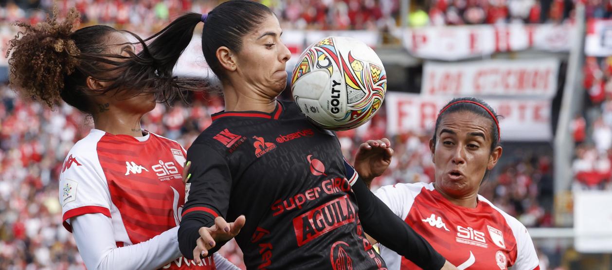 Catalina Usme, capitana del América, protege la pelota ante la marca de dos rivales. 