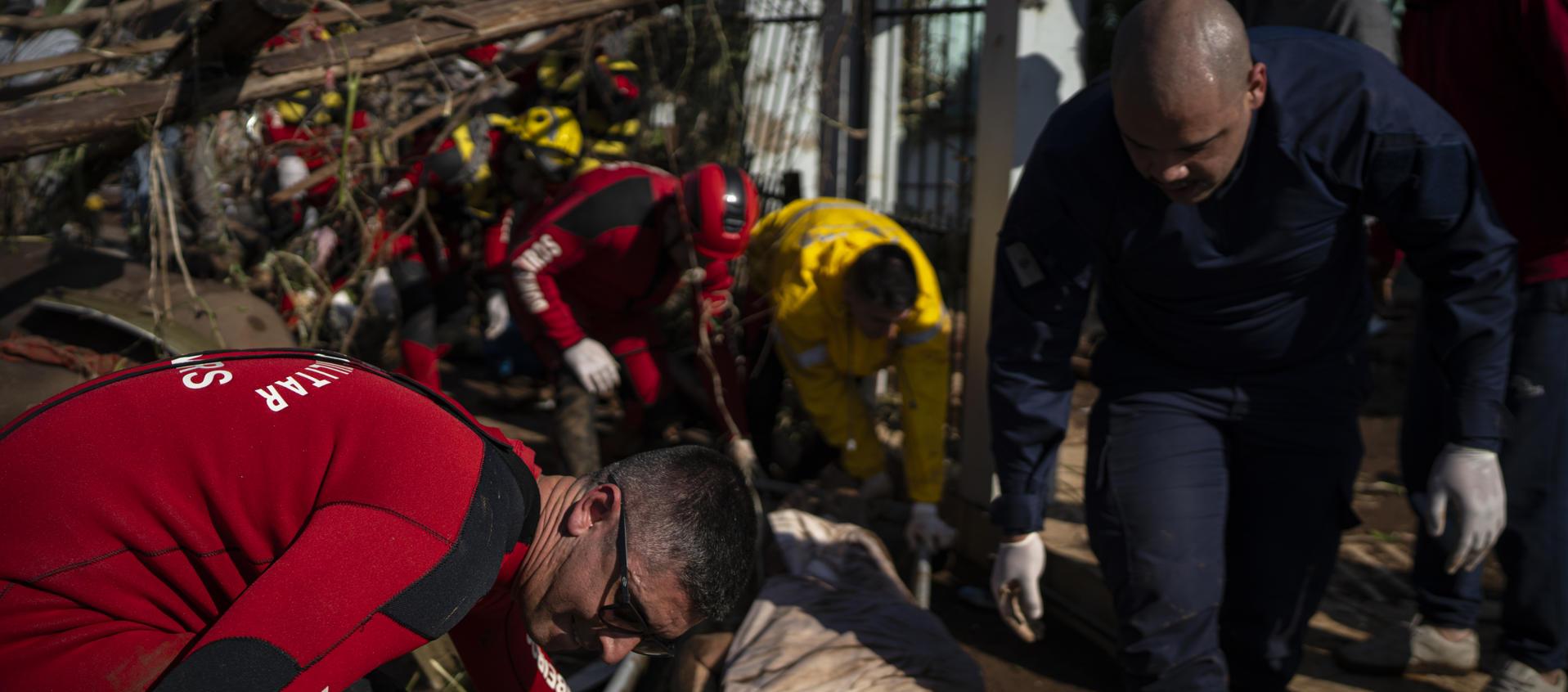 Bomberos retiran el cuerpo de una persona tras las inundaciones.