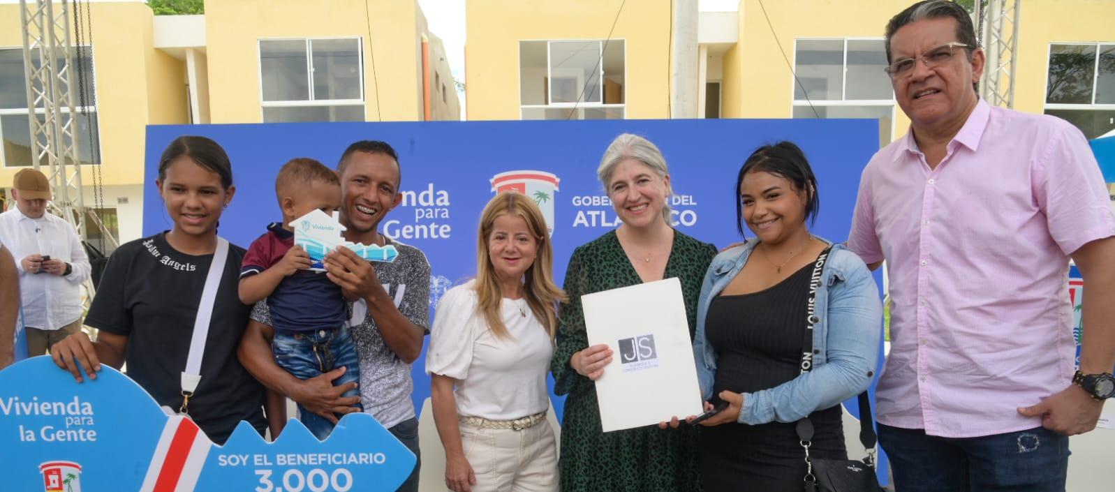 Gobernadora entregando título de propiedad a una familia beneficiada. Ministra de Vivienda estuvo presente.