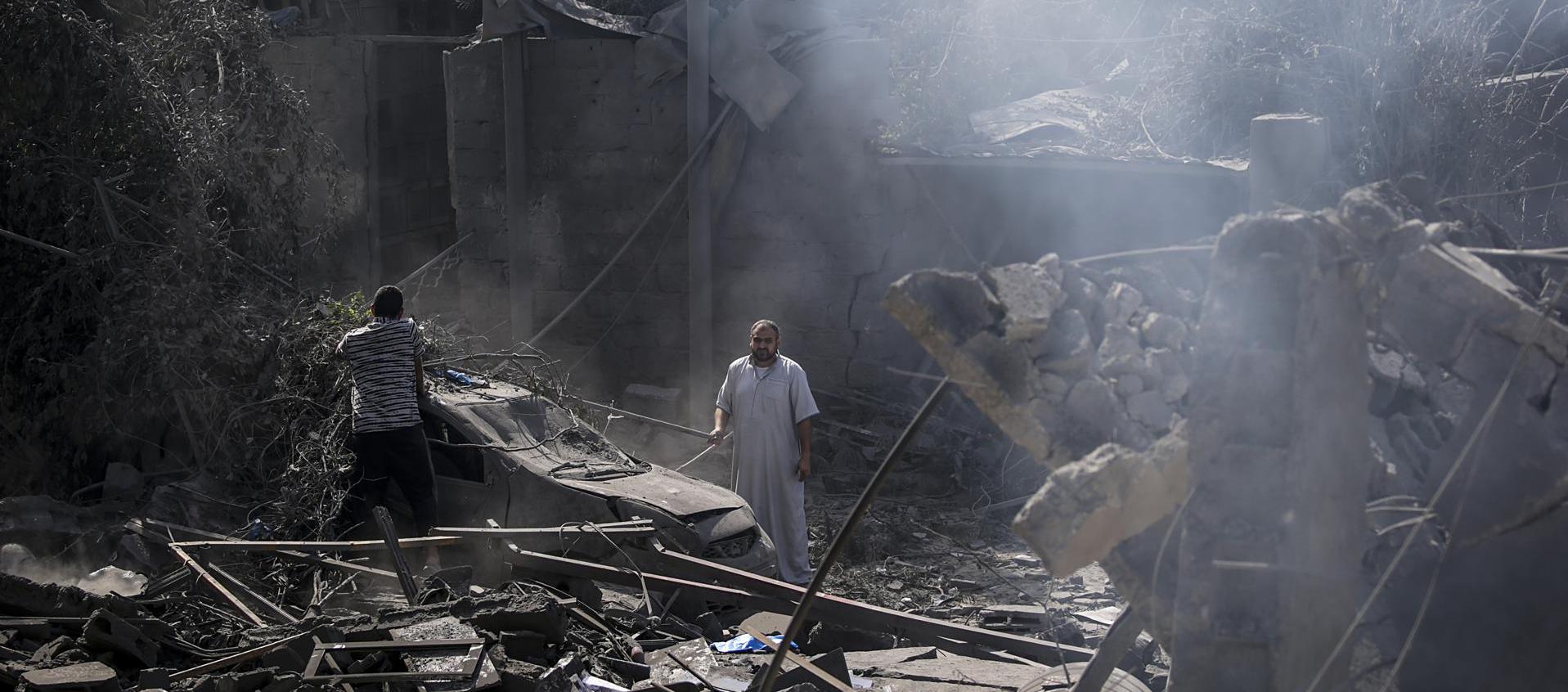 Dos palestinos miran los escombros de la casa destruida de la familia Al Shawa, en Gaza.